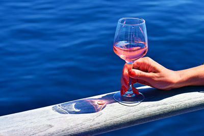 Lady's hand holding drink on a ship deck