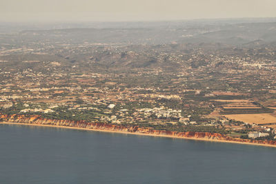 Aerial view of city by sea against sky