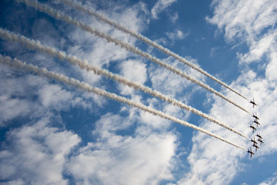 Low angle view of airplane emitting vapor trail against blue sky