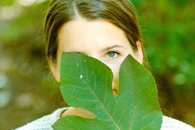 Close-up portrait of woman with green leaves