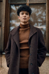 Portrait of young woman standing against wall