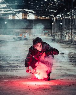 Man holding sparkler while crouching in factory