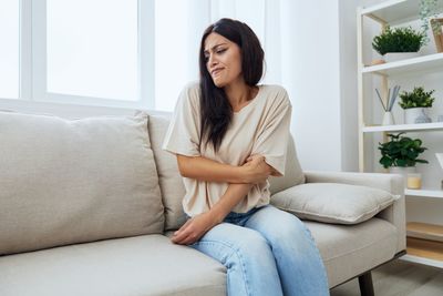 Young woman using laptop while sitting on sofa at home