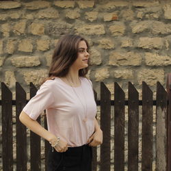 Young woman standing against brick wall