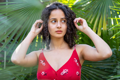 Portrait of young woman standing against plants