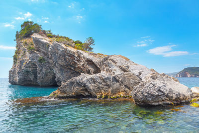 Rocky islet in the sea water . halfmoon beach in budva montenegro