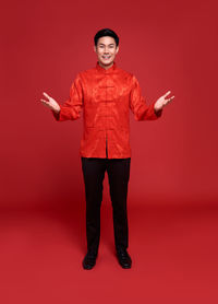 Full length portrait of happy man standing against red background