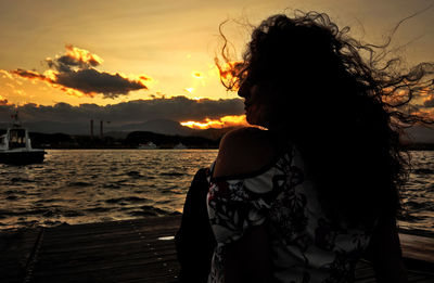 Woman looking at sea against sky during sunset