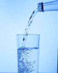 Close-up of glass pouring water against white background