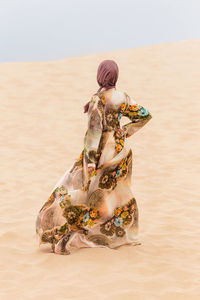 Woman standing on sand at beach against sky