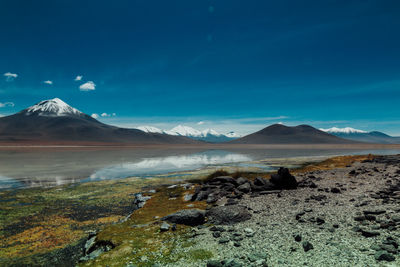 Scenic view of lake and mountains against blue sky