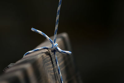 Close-up of rope tied on wood against black background