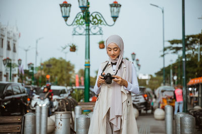 Portrait of young woman standing in city