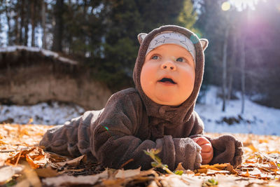 Cute baby in warm clothing lying on leaves