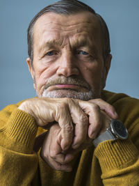 Portrait of senior man with hand on chin against blue background