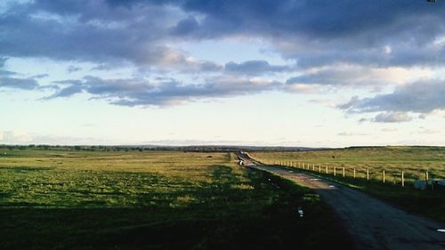 Scenic view of grassy field against cloudy sky