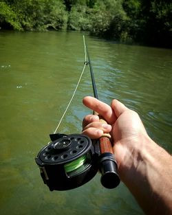 Midsection of man fishing in lake