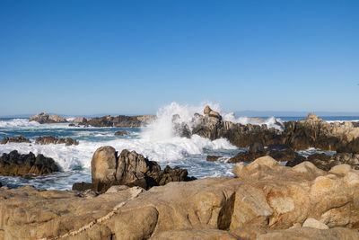 Rocks on beach against clear sky