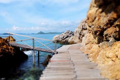 Jetty leading towards sea against sky