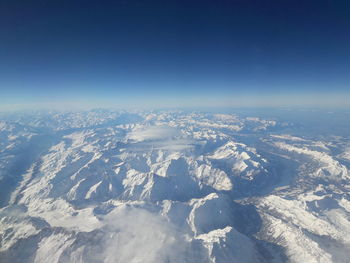 Aerial view of snowcapped mountain against blue sky