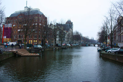 Boats in canal amidst buildings in city against sky