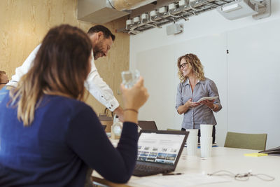 Smiling businesswoman sharing ideas with colleagues in meeting