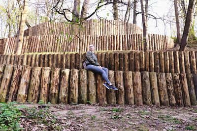 Full length of man jumping on tree trunk in forest