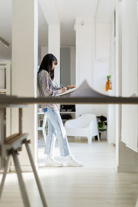 Businesswoman writing while leaning on column at office