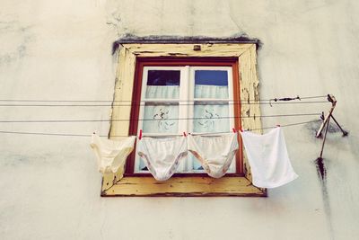 Low angle view of panties and napkin drying against old window