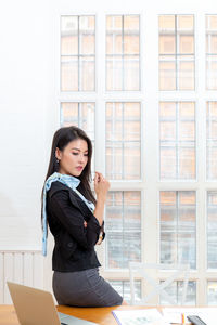 Full length of woman sitting against window