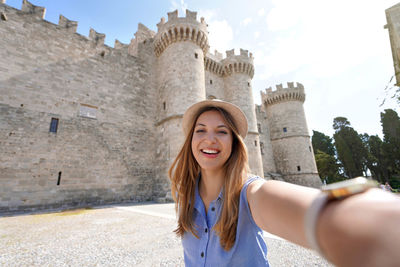 Woman taking self portrait in front of palace of the grand master of the knights of rhodes, greece