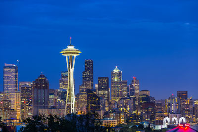 Illuminated city buildings against blue sky