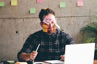 Architect with adhesive notes on face in office