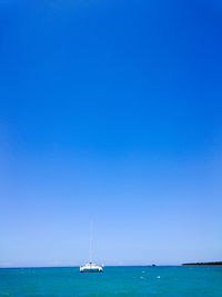 Sailboat sailing in sea against clear blue sky