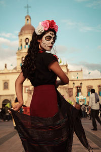 Portrait of young woman standing against built structure