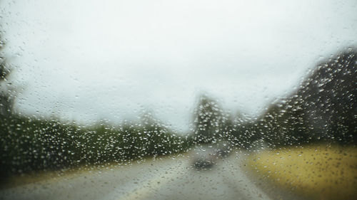 Close-up of water drops on window against sky