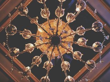 Low angle view of illuminated lighting equipment hanging from ceiling