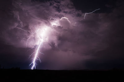 Lightning in sky over silhouette landscape