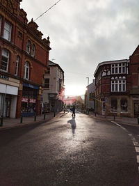 Man walking on road amidst buildings in city