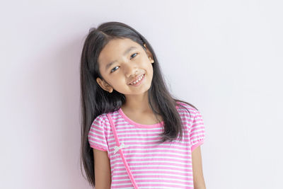 Portrait of a smiling girl standing against white background