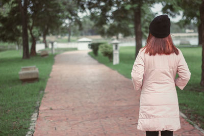 Rear view of woman standing on footpath