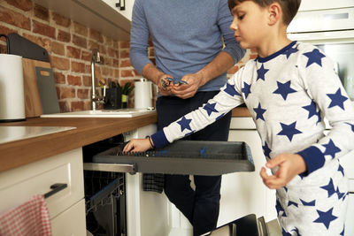 Boy arranging spoon in kitchen