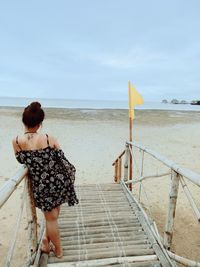 Rear view of woman on beach against sky