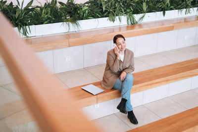 Adult business woman in stylish beige suit and jeans working on laptop at public place