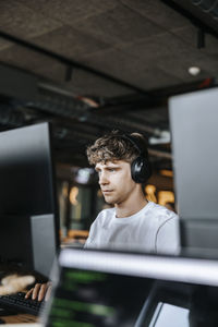 Young male programmer doing coding on computer while sitting at tech start up office