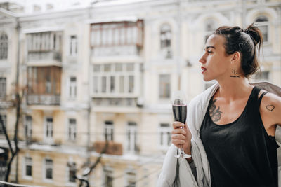 Woman looking away while standing against built structure