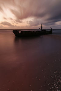 Silhouette boat in sea against sky during sunset