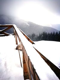 Traditional windmill on snow covered landscape against sky