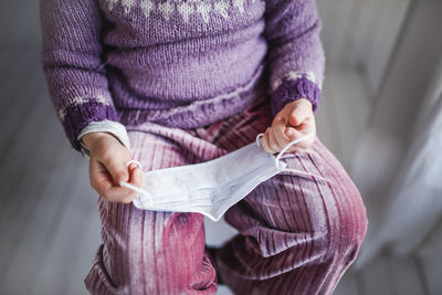 Midsection of woman holding paper while standing against wall