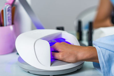 Cropped hand of customer putting hand in illuminated machine